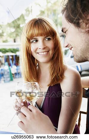 Stock Image - Couple clinking glasses with white wine. Fotosearch