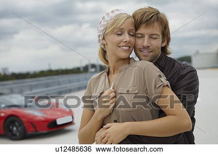 Couple close together near electric car View Large Photo Image Stock Photograph - Couple close together near electric car. Fotosearch