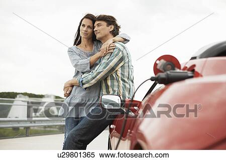 Couple close together near electric car View Large Photo Image Stock Photography - Couple close together near electric car. Fotosearch