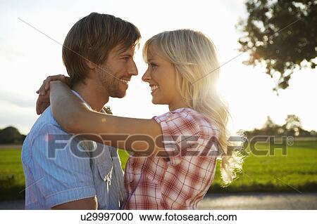 Stock Image - Couple close/hugging during sunset. Fotosearch