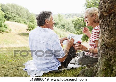 Couple doing crossword, sitting in park View Large Photo Image Stock Photo - Couple doing crossword, sitting in park. Fotosearch