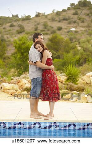 Stock Photo - Couple embracing by swimming pool. Fotosearch