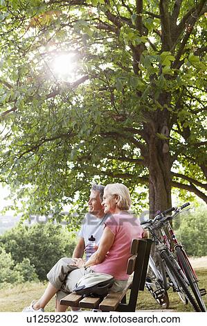 Stock Image - Couple having break on bench in park. Fotosearch