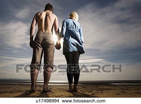 Picture - Couple holding hands on beach. Fotosearch