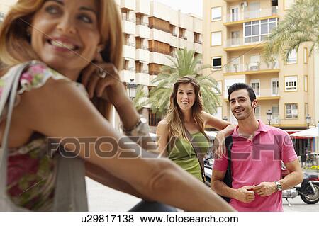 Stock Photo - Couple in city park with acquaintance. Fotosearch