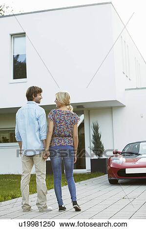 Couple in front of house + electric car View Large Photo Image Stock Image - Couple in front of house + electric car. Fotosearch