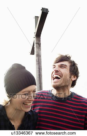 Stock Photo - Couple laughing under mountain cross. Fotosearch