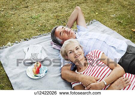 Stock Photograph - Couple laying on picnicblanket in grass. Fotosearch