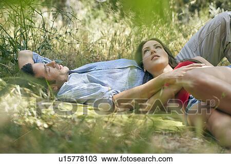 Couple lying on blanket in long grass View Large Photo Image Stock Image - Couple lying on blanket in long grass. Fotosearch