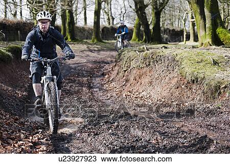Stock Image - Couple mountain biking in countryside. Fotosearch