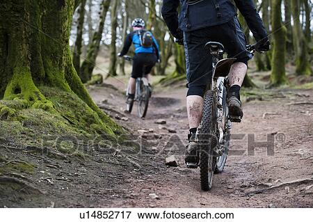 Stock Photo - Couple mountain biking in woods. Fotosearch
