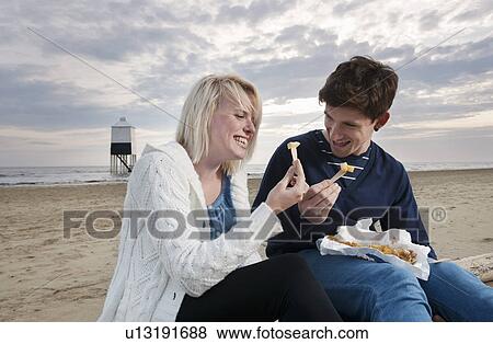 Couple on beach eating fish and chips View Large Photo Image Stock Photo - Couple on beach eating fish and chips. Fotosearch
