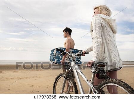 Stock Photo - Couple on beach with bike & boogie board. Fotosearch