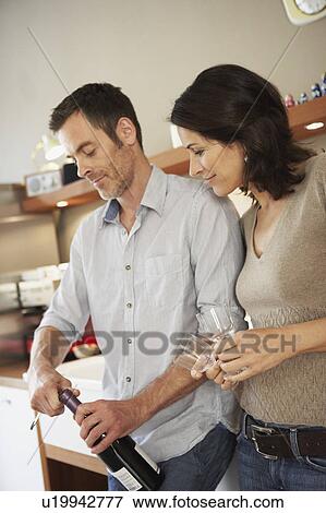 Stock Photo - Couple opening up bottle of wine. Fotosearch