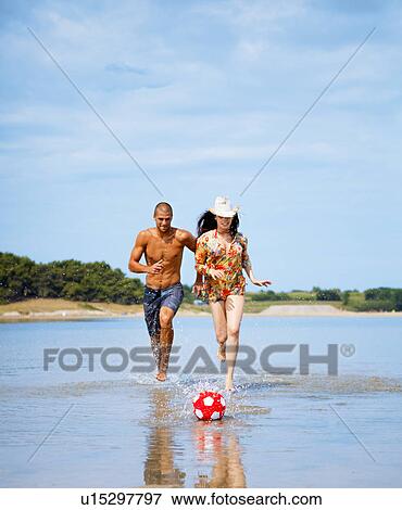 Stock Photo - Couple playing soccer at the beach. Fotosearch
