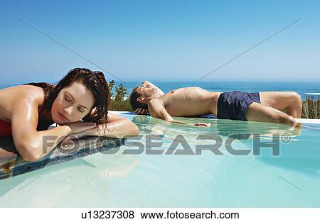Stock Photo - Couple relaxing by infinity pool. Fotosearch
