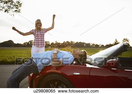 Stock Photography - Couple relaxing in nature around a car. Fotosearch