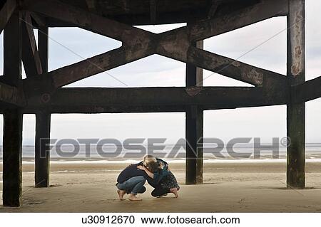 Couple sheltering on beach View Large Photo Image Stock Image - Couple sheltering on beach. Fotosearch