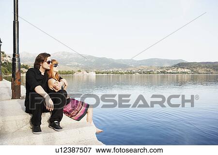 Stock Photo - Couple sitting by the sea. Fotosearch