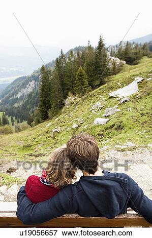 Stock Photo - Couple sitting on bench hugging. Fotosearch