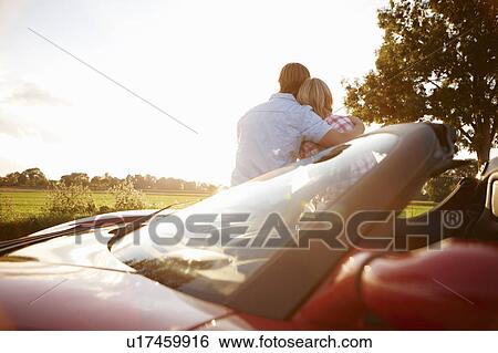 Couple sitting on electric sports car View Large Photo Image Stock Photograph - Couple sitting on electric sports car. Fotosearch