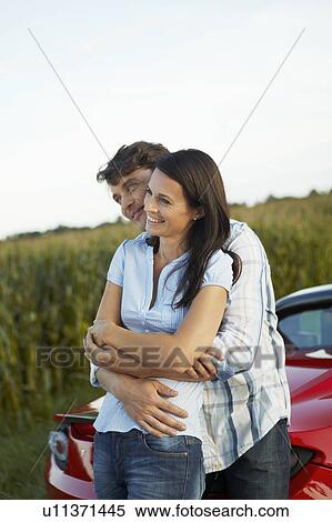 Couple standing by their electric car View Large Photo Image Stock Photography - Couple standing by their electric car. Fotosearch