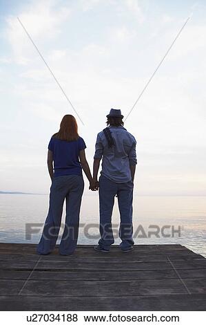 Couple standing on jetty View Large Photo Image Stock Photo - Couple standing on jetty. Fotosearch