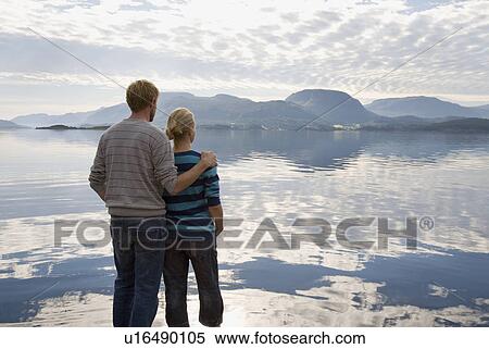 Stock Photography - Couple staring out across still sea. Fotosearch