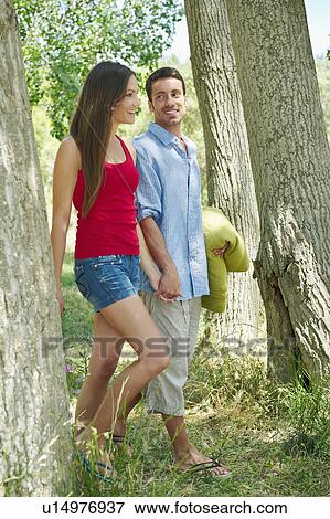 Stock Photo - Couple walking hand-in-hand in forest. Fotosearch