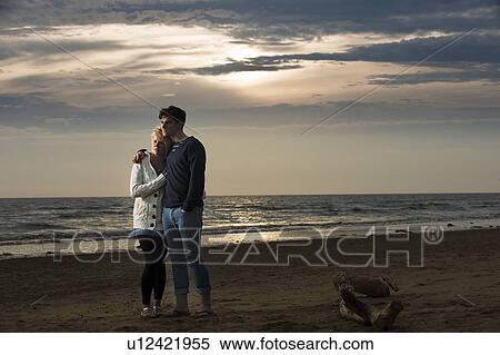 Stock Photography - Couple walking on beach at sunset. Fotosearch