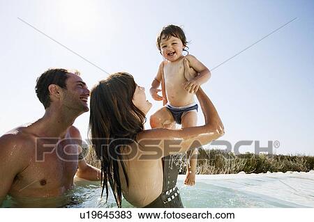 Stock Image - Couple with baby boy in outdoor pool. Fotosearch