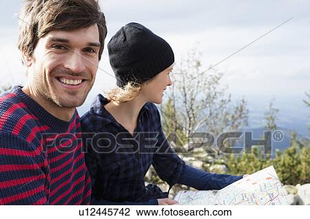 Stock Image - Couple with map in front of landscape. Fotosearch