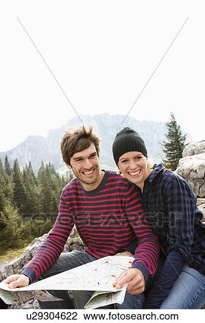 Couple with map sitting on rock View Large Photo Image Stock Image - Couple with map sitting on rock. Fotosearch