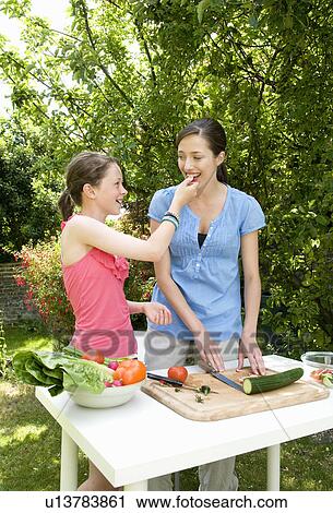 Daughter feeds mother salad, outdoors View Large Photo Image Stock Image - Daughter feeds mother salad, outdoors. Fotosearch