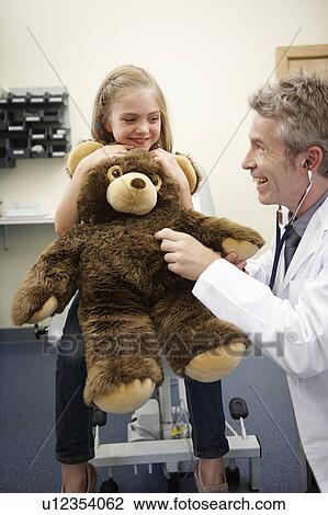 Stock Image - Doctor listening to teddy bear's heart. Fotosearch