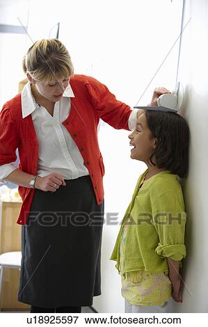 Stock Photo - Doctor measuring height of young girl. Fotosearch