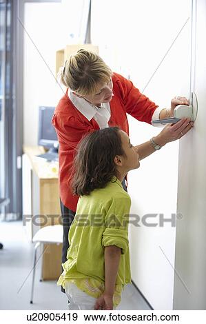 Doctor measuring height of young girl View Large Photo Image Stock Photo - Doctor measuring height of young girl. Fotosearch