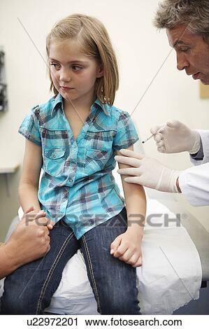 Stock Image - Doctor siting on desk in surgery. Fotosearch