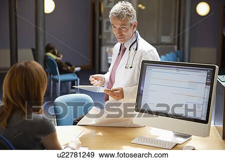 Doctor sitting on desk in reception View Large Photo Image Stock Photo - Doctor sitting on desk in reception. Fotosearch