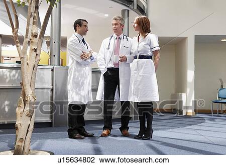 Stock Image - Doctors and nurse talking in surgery. Fotosearch
