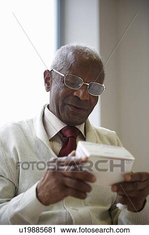 Stock Image - Elderly black man reading medicine box. Fotosearch