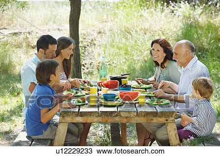 Family eating meal on outdoor table View Large Photo Image Stock Image - Family eating meal on outdoor table. Fotosearch