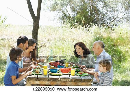 Family eating meal on outdoor table View Large Photo Image Stock Image - Family eating meal on outdoor table. Fotosearch