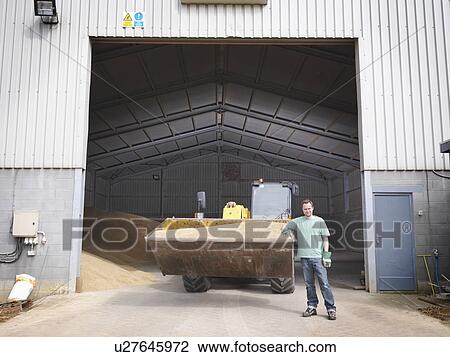 Stock Image - Farmer in front of grain store. Fotosearch