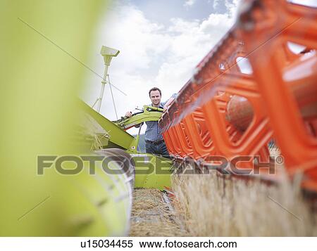 Stock Photography - Farmer inspecting machinery. Fotosearch