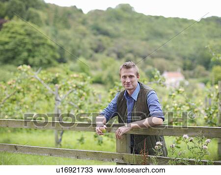 Farmer leans on fence outside orchard View Large Photo Image Stock Image - Farmer leans on fence outside orchard. Fotosearch