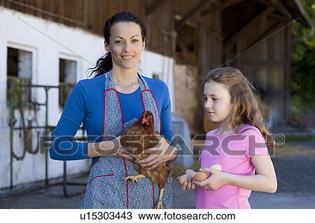 Stock Image - Farmwoman with hen, daughter with eggs. Fotosearch