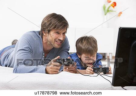 Father and son playing a video game View Large Photo Image Stock Photo - Father and son playing a video game. Fotosearch