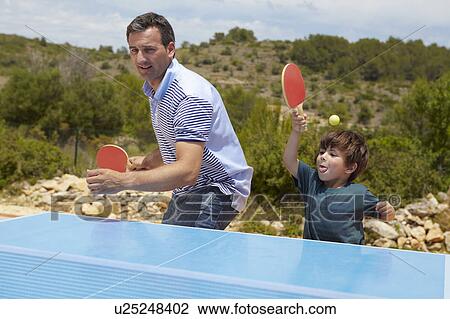 Stock Image - Father and son playing table tennis. Fotosearch