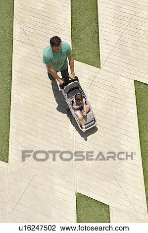 Stock Image - Father pushing push-chair. Fotosearch